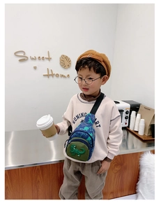 Detailed view of kids dinosaur chest bag with adjustable strap worn by a child model