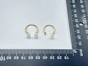 Dettaglio di orecchini a C placcati oro 18K con perle bianche e perline dorate