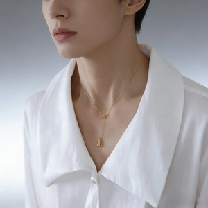Minimalist gold teardrop pendant necklace on fine chain for women wearing a white shirt
