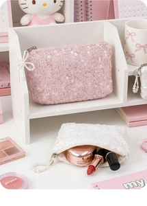 Detail of pink and white sequin pouches with pearl zippers and cosmetic storage