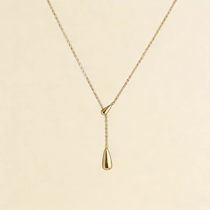 Detail of gold-plated drop pendant necklace featuring a polished water drop and fine link chain