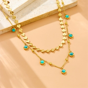 Detail of double-layer gold chain necklace with turquoise beads and shell-shaped elements