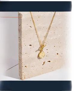 Macro detail of gold OT clasp and queen coin pendant on minimalist silver necklace