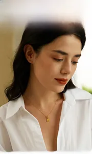 Close-up of golden OT buckle necklace with a coin queen pendant worn by a model