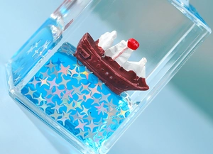 Macro shot of liquid wave paperweight with miniature ship and silver star glitter inside