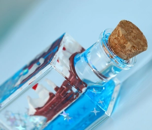 Close-up of a blue fluid drift bottle with a miniature ship and sparkling glitters