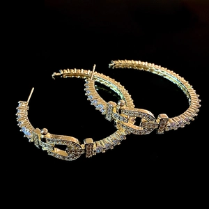 Gros plan de boucles d'oreilles fer à cheval dorées serties de cristaux scintillants