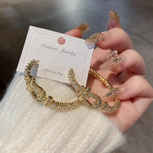 Créoles en forme de C dorées avec zircons et tiges en argent 925 portées par un mannequin