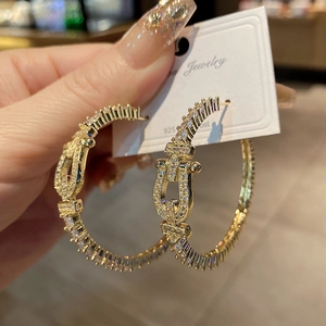 Détail macro de créoles fer à cheval dorées avec zircons et tiges en argent 925 pur