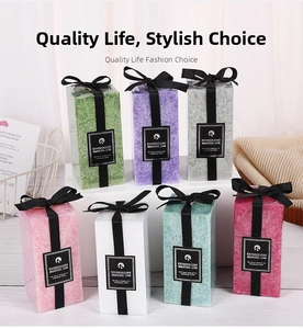 Detail of square textured pillar candles with black ribbon bows and essential oil labels