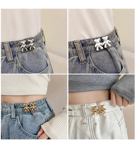 Detailed view of bear-shaped waist tighteners in silver and gold on denim fabric
