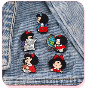 Vue détaillée de cinq épingles en émail Mafalda colorées sur un tissu en denim bleu
