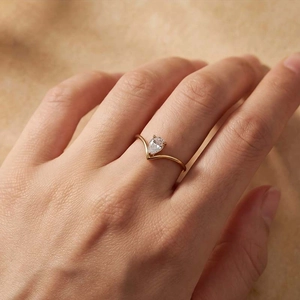 Close-up of elegant V-shaped gold ring with pear-cut zircon stone worn on finger