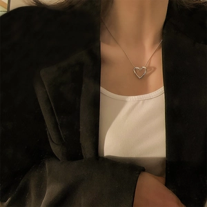Detail of silver hollow heart pendant necklace styled with a minimal snake chain