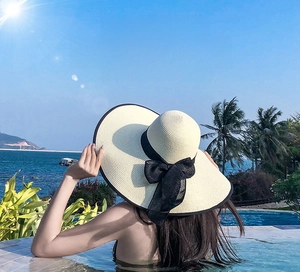 Detail of wide brim straw sun hat with black ribbon bow for summer beach vacation