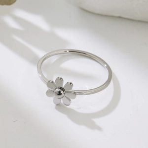 Macro top view of a polished silver daisy ring on a white minimalist background