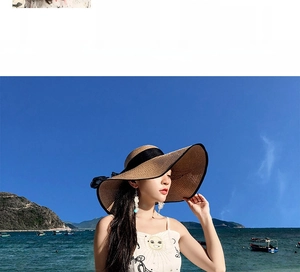 Detail of a wide brim straw sun hat with black ribbon bow against beach background