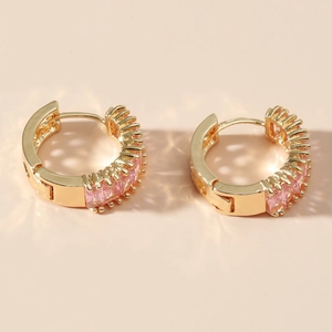 Close-up of gold hoop earrings featuring pink emerald-cut stones in a channel setting