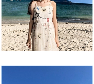 Detailed close-up of cream-colored sundress with celestial sun and moon embroidery