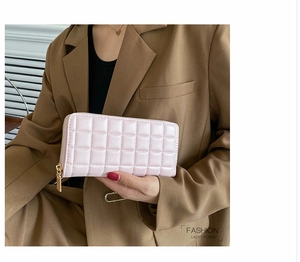 Detail of pink quilted PU leather wallet with gold metal zipper held by a model