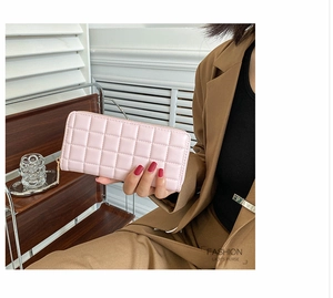 Detail of pink quilted plaid long wallet held by professional woman in office attire