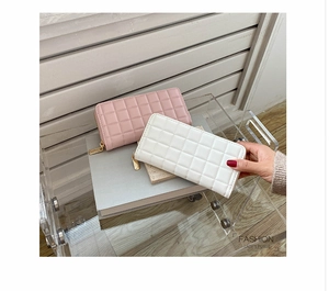 Detail of pink and white quilted PU leather wallets with gold zippers on a display stand