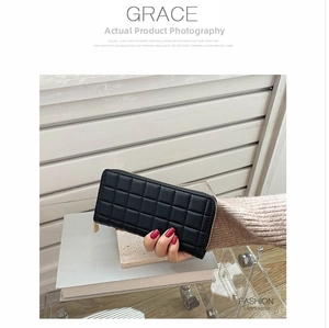 Detailed view of women's black long wallet with quilted pattern and gold zipper closure