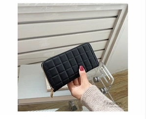 Detail of a black quilted long purse for women featuring a gold zipper and hand-held view