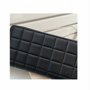 Macro shot of black quilted faux leather purse featuring checkered pattern and zipper