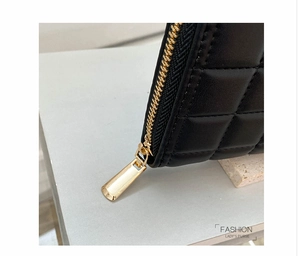 Close-up of black quilted leather wallet featuring premium gold zipper and detailed stitching