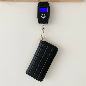 Women's black quilted long wallet on a scale showing a precise weight of 0.155kg