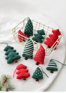 Detailed view of ten red and green knitted Christmas tree ornaments on white faux fur background
