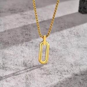 Golden stainless steel geometric oval pendant necklace on a textured grey stone surface