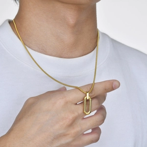 Close-up of polished gold oval pendant on a refined box chain worn by a model