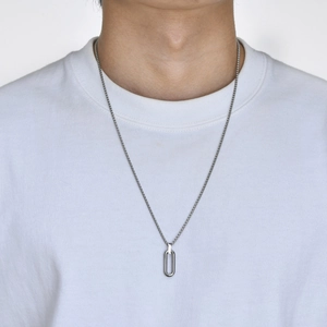 Close-up of a silver minimalist oval geometric pendant on a stainless steel chain