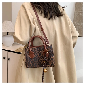 Detail of trendy leopard print crossbody bag with woven rope and golden bell charm