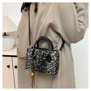 Detail of grey leopard print crossbody bag with black handles and golden spherical charm