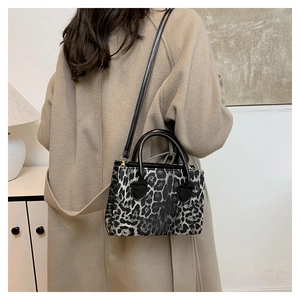 Detail of leopard print crossbody bag with black leather handle on camel winter coat