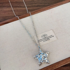 Gros plan du pendentif étoile argenté avec texture martelée et cristaux sur lin blanc