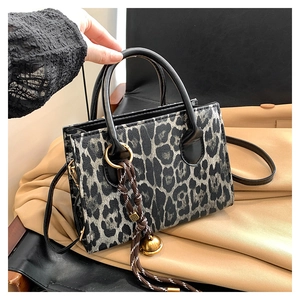 Detail of leopard print crossbody bag with woven cord and gold ball charm accessory