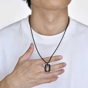 Detail shot of a minimalist black matte rectangular pendant on a ball chain for men