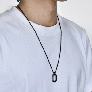 Detail of a men's black geometric hollow rectangle pendant worn on a white t-shirt