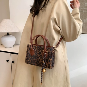 Stylish leopard print crossbody bag with brown faux leather straps and gold bell charm