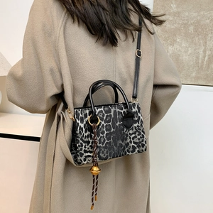 Elegant leopard print crossbody bag with gold charm on a woman in a beige coat