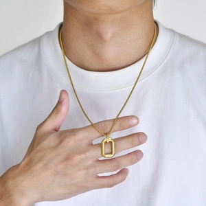 Close-up of a men's gold rectangle geometric cutout pendant on a sleek chain