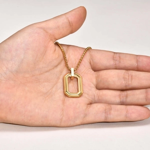 Detail of a minimalist gold geometric octagonal pendant on a round box chain being held