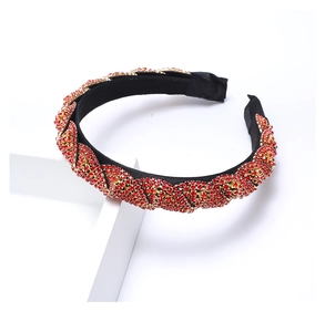 Detail of red and gold rhinestones woven on a black fabric twisted headband