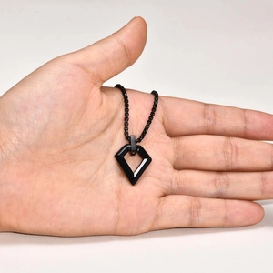 Detail of hand holding a black minimalist geometric shield pendant necklace with matte finish