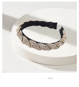 Close-up of luxury black fabric headband with golden spiral chain and sparkling rhinestones