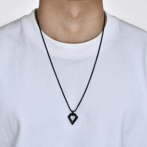 Close-up of a minimalist black geometric rhombus pendant necklace worn by a male model